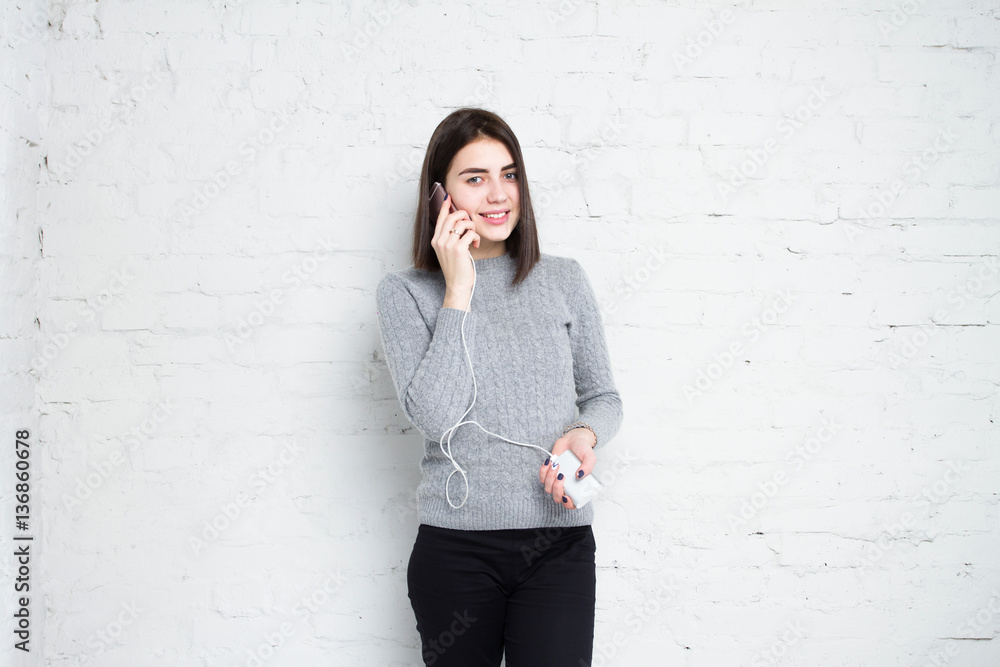 Powerbank in hands. Girl talking on the phone in smartphone and charges her phone. Young beautiful girl smiles with a phone and charging in his hand Powerbank in hands. Girl talking on the phone in smartphone and charges her phone. Young beautiful girl smiles with a phone and charging in his hand