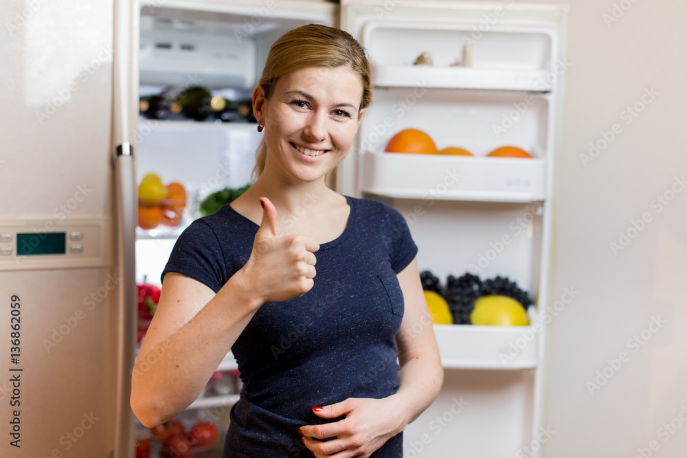 Healthy Eating Concept . Beautiful Young Woman near the Refrigerator with healthy food. Fruits and Vegetables Healthy Eating Concept . Beautiful Young Woman near the Refrigerator with healthy food. Fruits and Vegetables