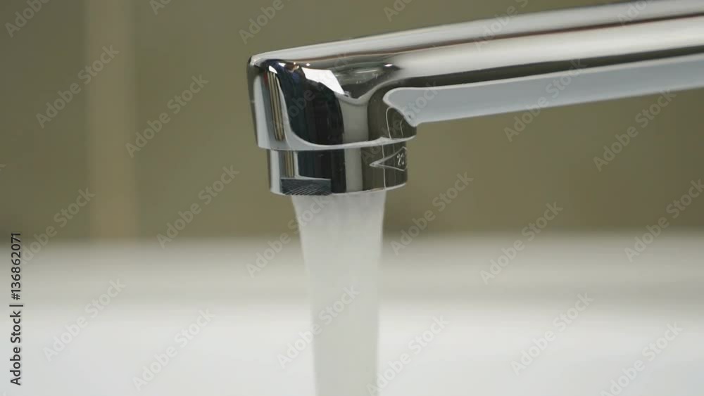 Chrome-plated tap in bathroom. Weak flow of water pouring from chrome-plated tap. Close-up Chrome-plated tap in bathroom. Weak flow of water pouring from chrome-plated tap. Close-up