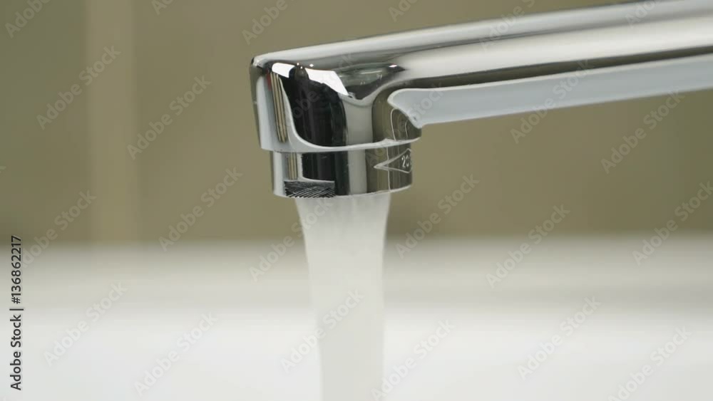 Chrome-plated tap in bathroom. Strong flow of water pouring from chrome-plated tap. Close-up Chrome-plated tap in bathroom. Strong flow of water pouring from chrome-plated tap. Close-up