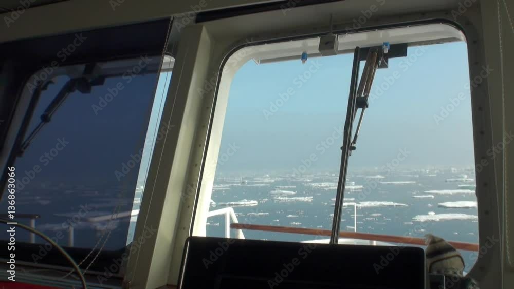 View from the cabin window on the background of the captains of floating ice. Wilderness. Extreme tourism and travel in the cold polar north. Scenic coastline and blue water. View from the cabin window on the background of the captains of floating ice. Wilderness. Extreme tourism and travel in the cold polar north. Scenic coastline and blue water.