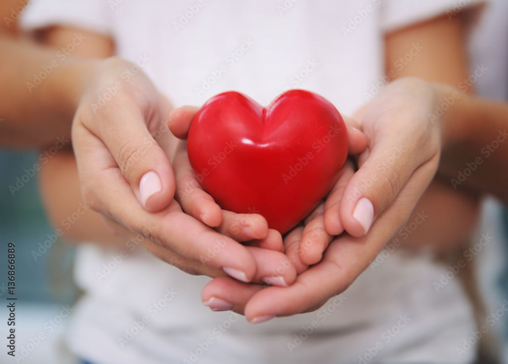 Hands of child and adult woman holding red heart, closeup Hands of child and adult woman holding red heart, closeup