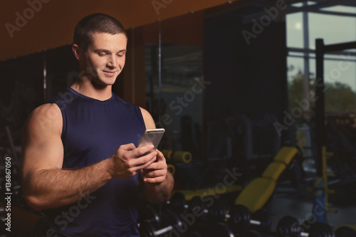 Young handsome man with cellphone in gym