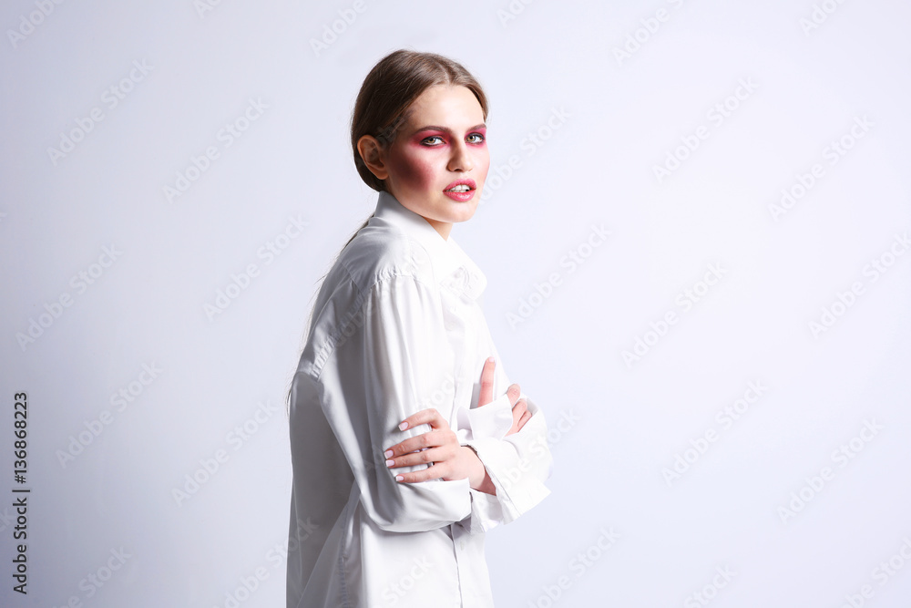 Young model with bright makeup on light background