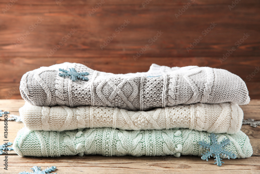 Stack of woolen clothes on wooden background, closeup