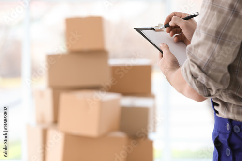 Man holding clipboard on blurred boxes background photo