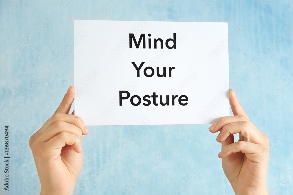 Hands holding paper with phrase MIND YOUR POSTURE on light background Hands holding paper with phrase MIND YOUR POSTURE on light background