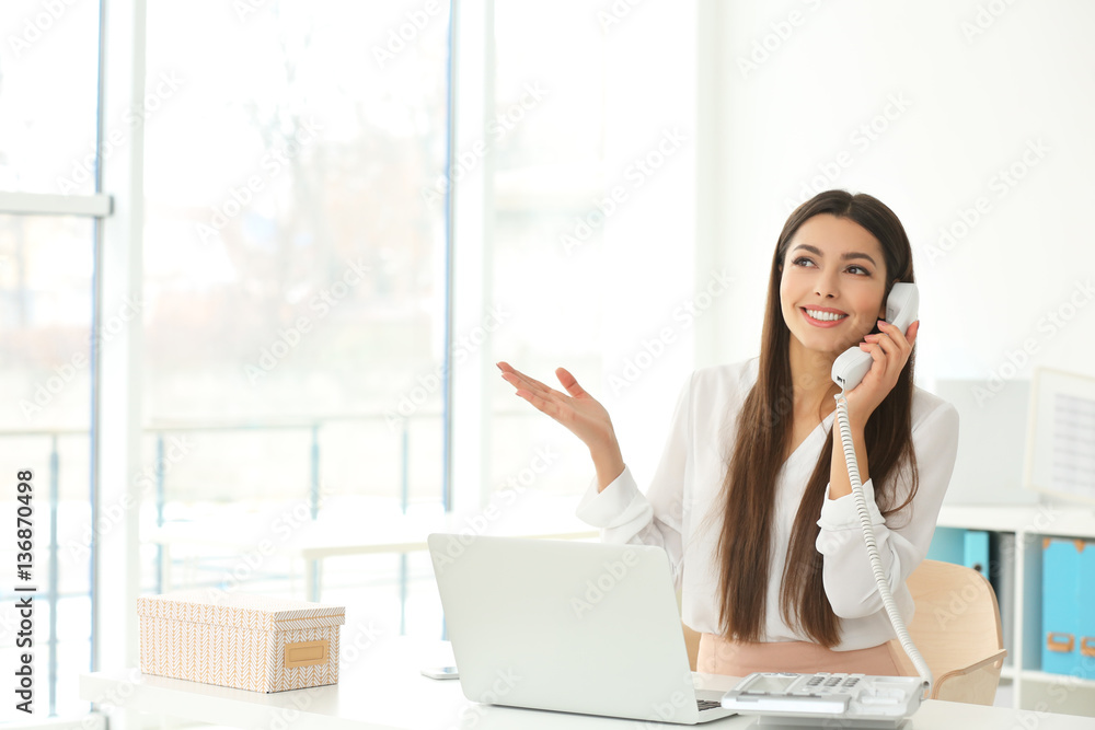 Beautiful young woman talking by telephone while working in office Beautiful young woman talking by telephone while working in office