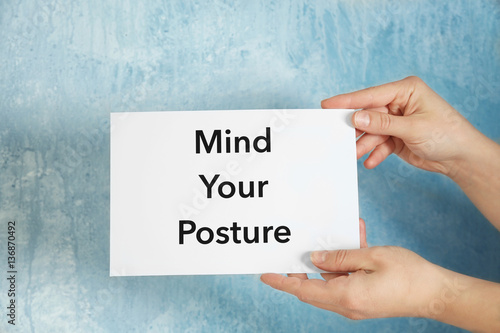 Hands holding paper with phrase MIND YOUR POSTURE on light background