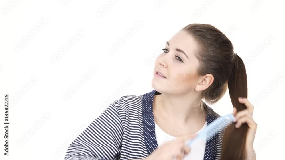 Woman wearing bath robe combing her healthy hair with blue comb. Young female with beauty straight long brown hairs -studio shot isolated on white background 4K ProRes HQ codec Woman wearing bath robe combing her healthy hair with blue comb. Young female with beauty straight long brown hairs -studio shot isolated on white background 4K ProRes HQ codec