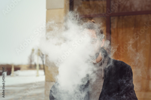 The man in the smoke. He smokes electronic cigarette. Evaporate.
