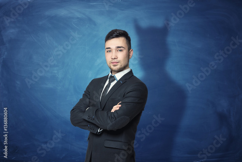 Foto Businessman on blue chalkboard background with his shadow having devil horns