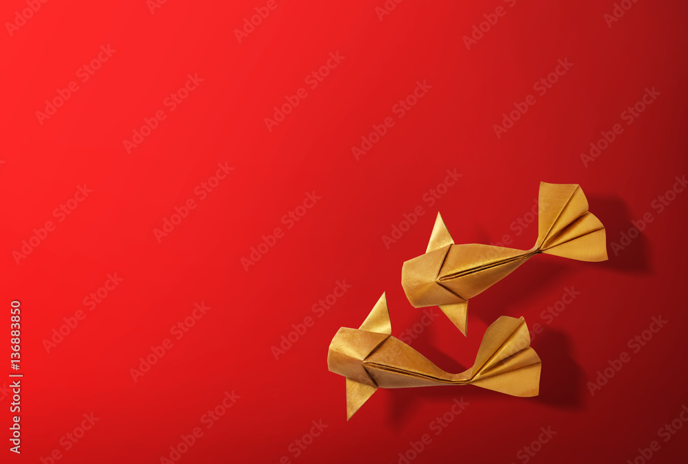 Naklejka premium Handmade paper craft gold color origami koi carp fish on red background with empty space. 