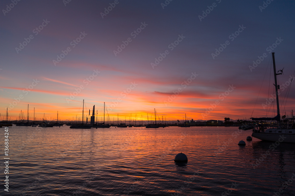 Pink, yellow, red, orange sunset sky in California, San Diego. Sailboats, boats. Silhouette