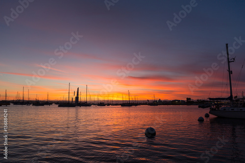 Pink, yellow, red, orange sunset sky in California, San Diego. Sailboats, boats. Silhouette