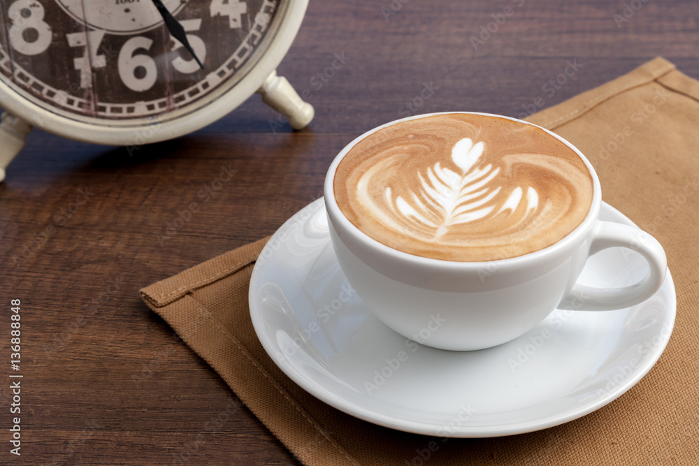 Coffee cup of rosetta latte art place on napkin on wooden table