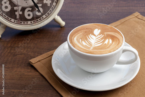 Obraz na płótnie Coffee cup of rosetta latte art place on napkin on wooden table w salonie