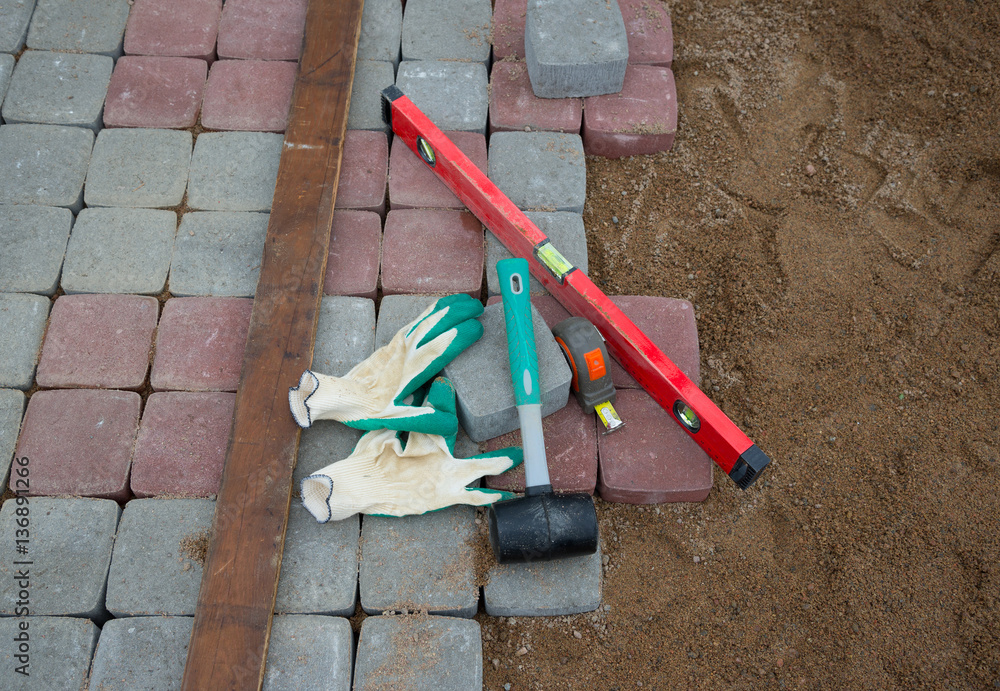  stone blocks rubber hammer level gloves and tape measure