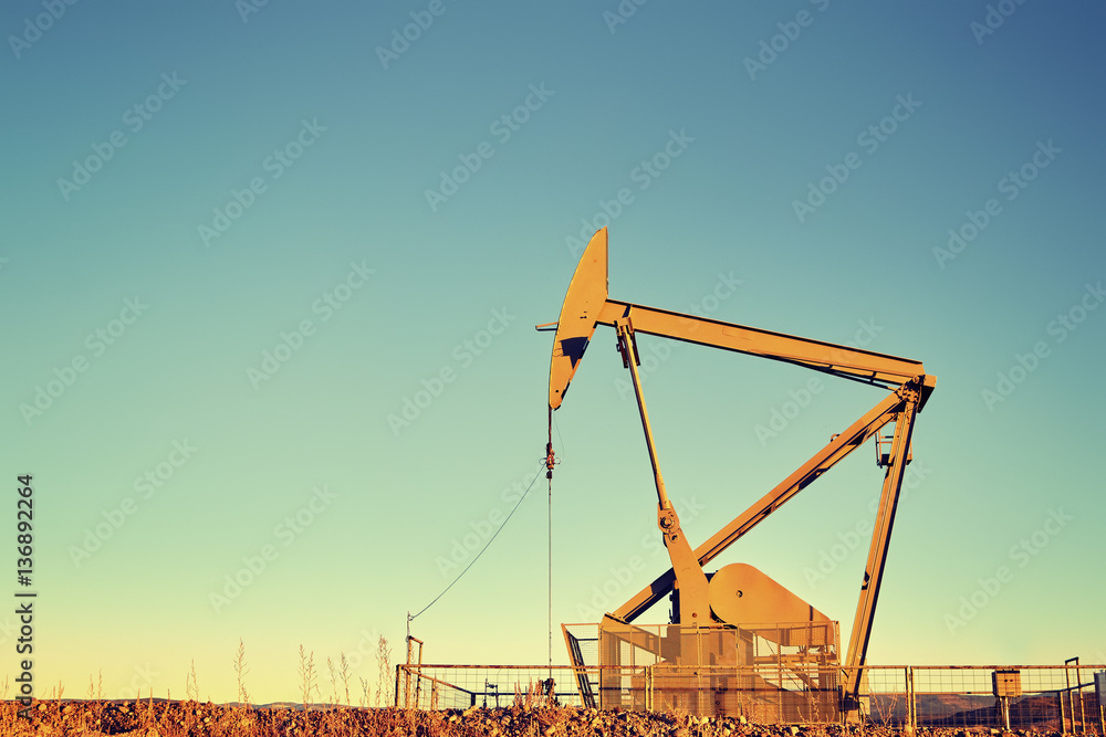 Fototapeta premium Vintage color toned an old oil pump at sunset, oil business concept, copy space.