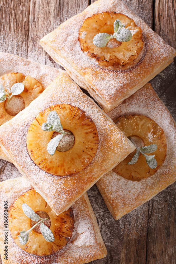 Fototapeta premium Freshly baked puff pastry pies with pineapple close-up. vertical top view