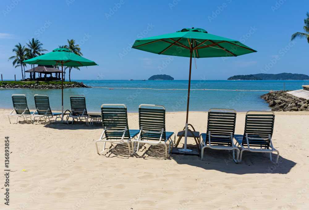 Lounge chairs with sun umbrella on a beach in Kota Kinabalu, Sabah Borneo, Malaysia.