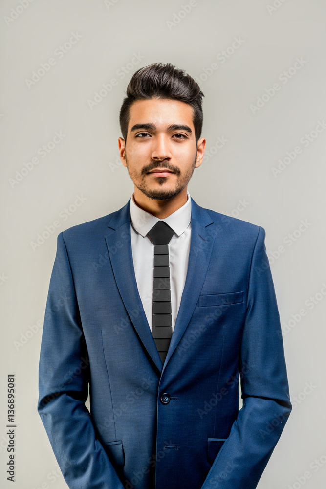 Young attractive man in a blue suit on a gray background. Isolated Young attractive man in a blue suit on a gray background. Isolated