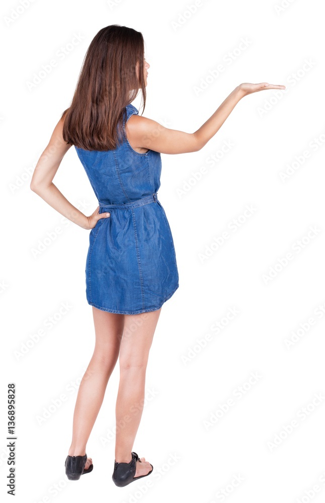 Back view of Beautiful woman in jeans dress and sandals Holds h Back view of Beautiful woman in jeans dress and sandals Holds h