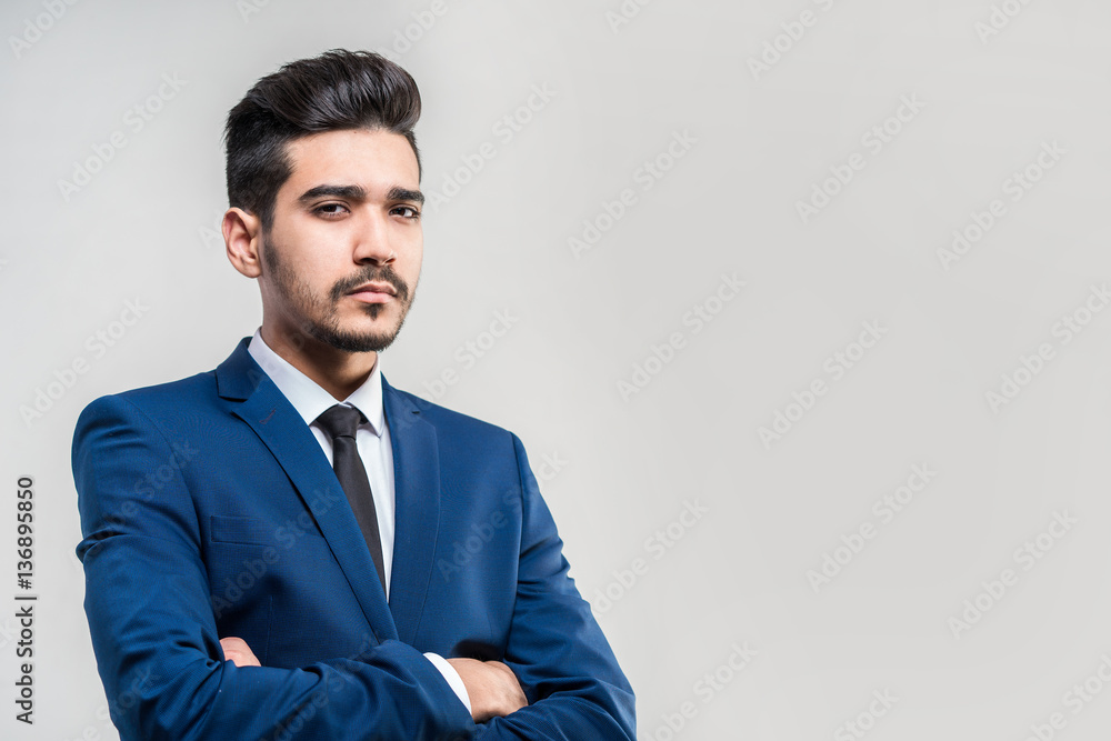 Young attractive man in a blue suit on a gray background. Isolated Young attractive man in a blue suit on a gray background. Isolated