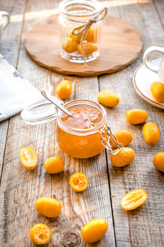 kumquat on plate and jam in jar at wooden table