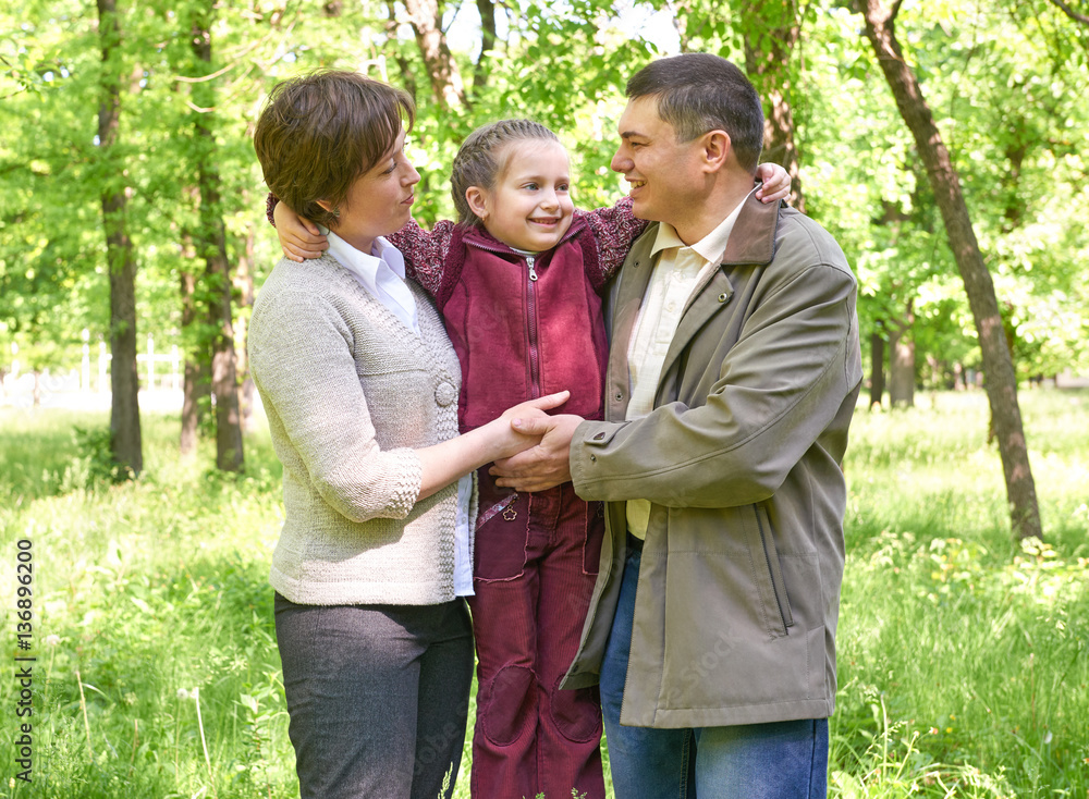 happy family with child in summer park, sunlight, green grass and trees happy family with child in summer park, sunlight, green grass and trees