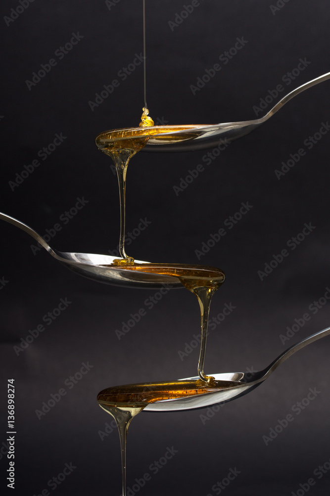 Honey pouring from spoon against a dark background
