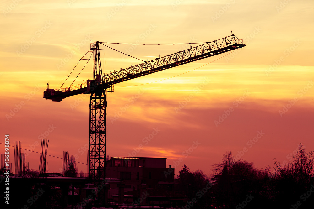 Sunset in vibrant colors and a crane in industrial area