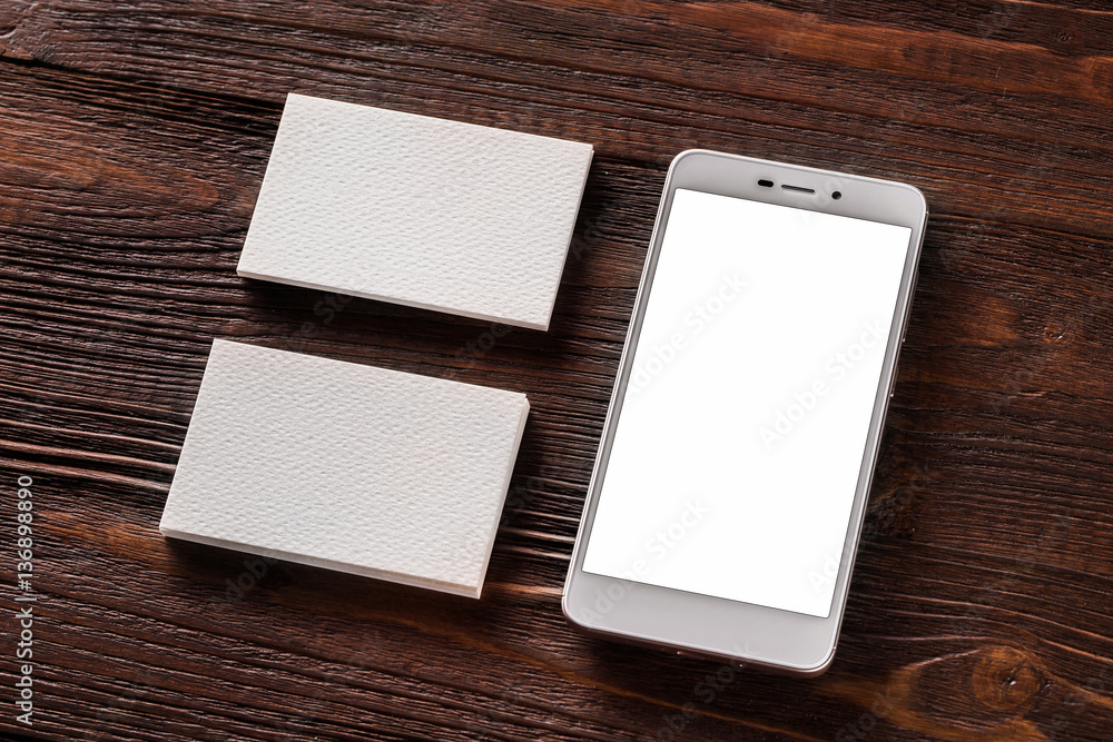Mockup of cellphone and two business cards at brown wooden board Mockup of cellphone and two business cards at brown wooden board