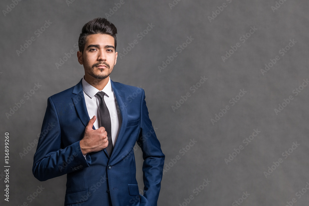 Young attractive man in a blue suit on a gray background Young attractive man in a blue suit on a gray background
