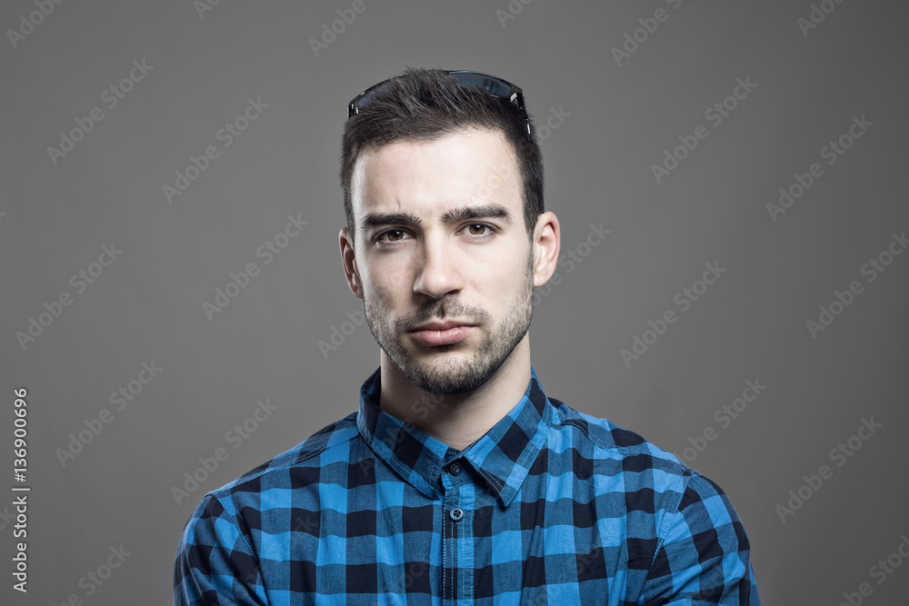 Fototapeta premium Moody portrait of skeptical young man frowning face looking at camera over gray studio background. 