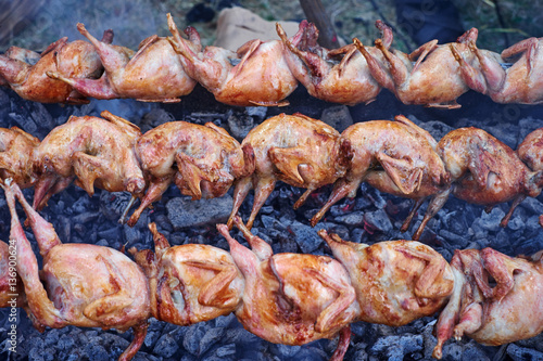 Chicken grilled on skewers over coals