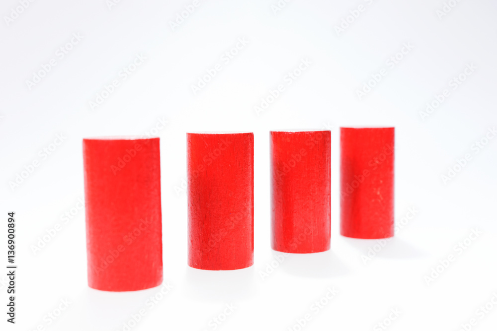 Four red round wooden building blocks in a row one behind the other Four red round wooden building blocks in a row one behind the other