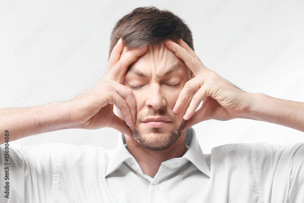 Young man with headache on white background