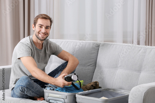 Man packing his grey suitca...