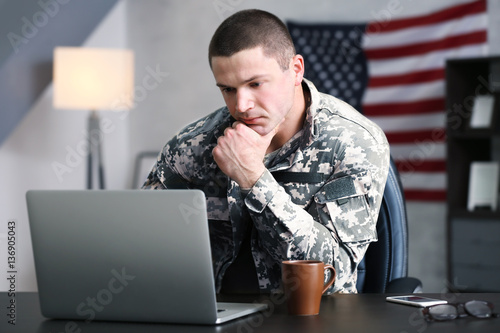 Soldier working with laptop in headquarters building