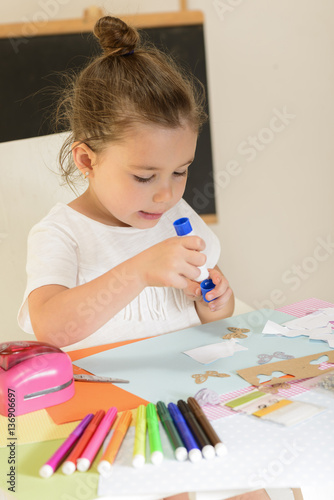 Beautiful little girl sticking with glue pieces of paper on the art lesson class. Children education concept. Kids crafts. Learn Study Education School Knowledge Concept