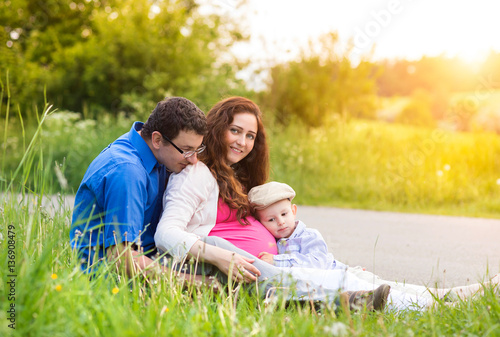 Young family on a walk in green sunny summer nature