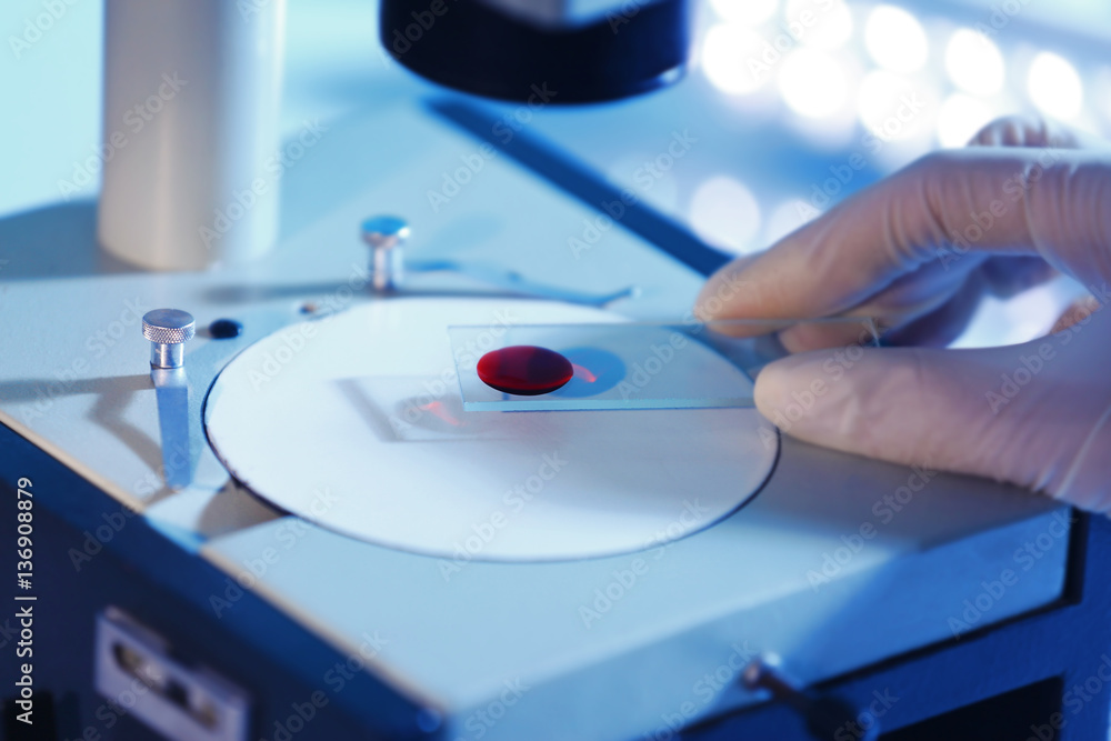 Scientist hand holding test sample under microscope in laboratory Scientist hand holding test sample under microscope in laboratory
