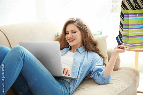 Beautiful young woman doing online shopping at home