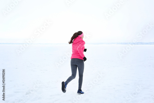 Back view of young woman jogging on winter day