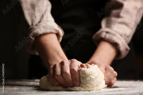 Photos Male hands kneading dough on sprinkled with flour table, closeup