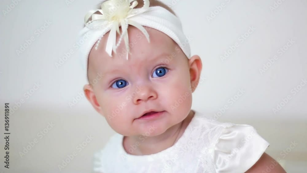 baby girl in white dress and headband sitting on a little iron bed baby girl in white dress and headband sitting on a little iron bed
