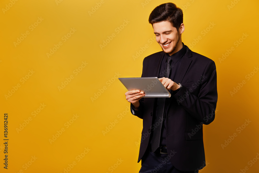 Young businessman smiling in the morning on a yellow background. dressed in a suit. gadget in their hands. concept business. excellence mood. Young businessman smiling in the morning on a yellow background. dressed in a suit. gadget in their hands. concept business. excellence mood.