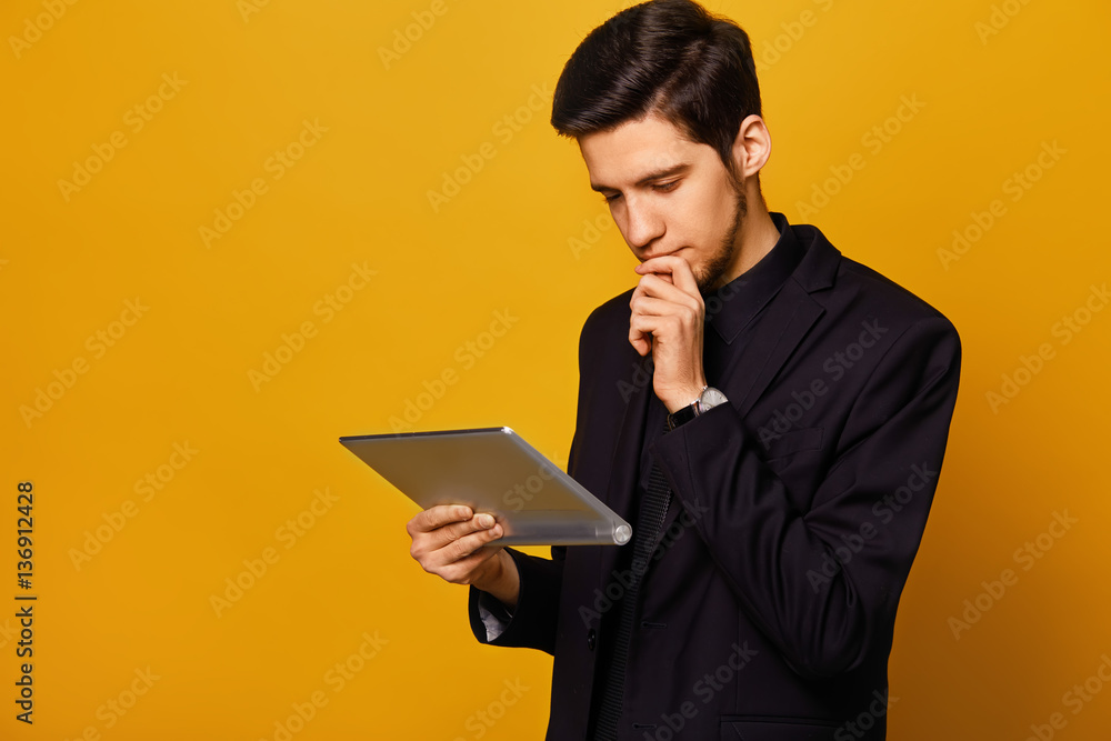 Young businessman smiling in the morning on a yellow background. dressed in a suit. gadget in their hands. concept business. excellence mood. Young businessman smiling in the morning on a yellow background. dressed in a suit. gadget in their hands. concept business. excellence mood.