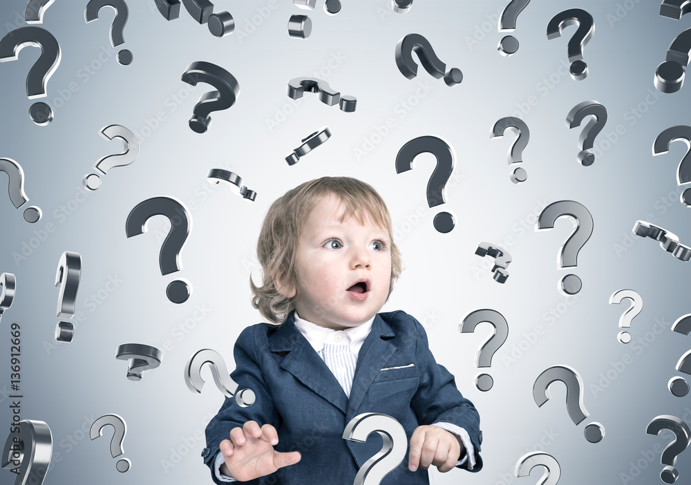 Baby boy and question marks on gray wall Baby boy and question marks on gray wall